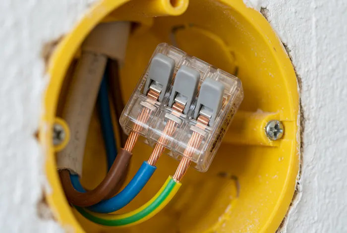 Gros plan macro d'une borne Wago transparente dans une boîte d'encastrement jaune placo